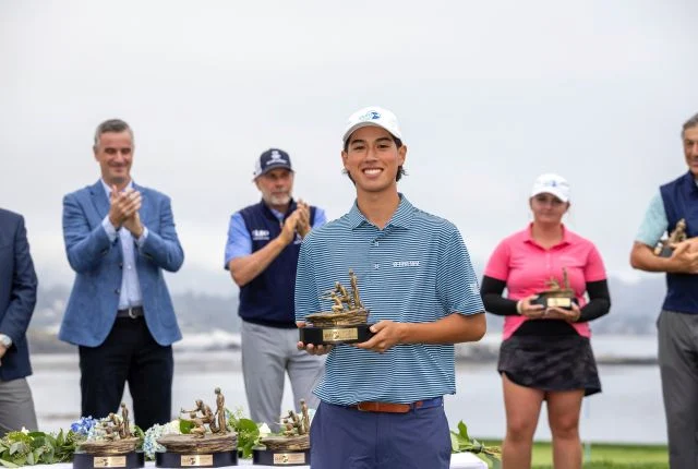 Julio Rodas Rhim smiles while holding his tournament trophy as spectators applaud in the background