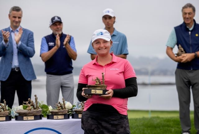 Margaret Kerr smiles in a pink polo while holding her bronze trophy during a tournament ceremony